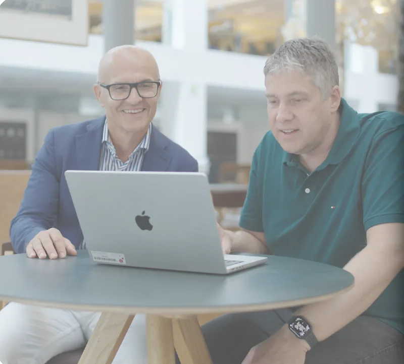 An IT leader and a colleague reviewing work on a laptop